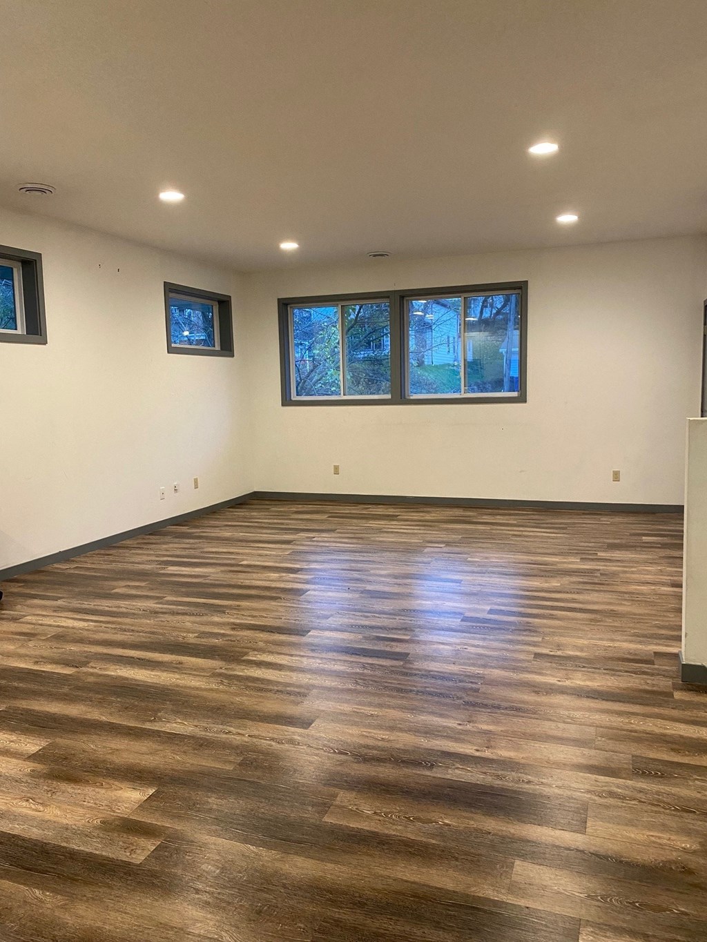 a living room with wood floors and white walls and windows