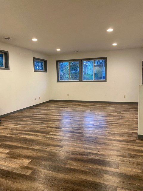 a living room with wood floors and white walls and windows