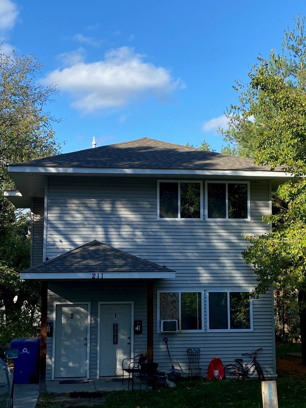 a gray house with a blue sky and trees
