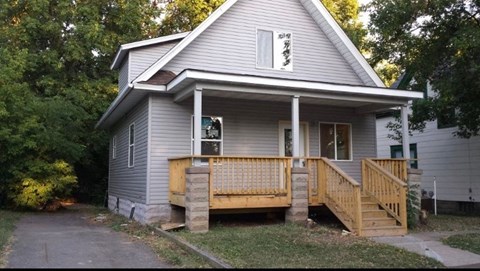 A house with a grey siding and a wooden porch.