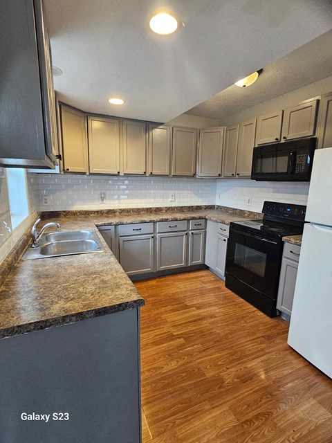 A kitchen with a black granite countertop and white appliances.