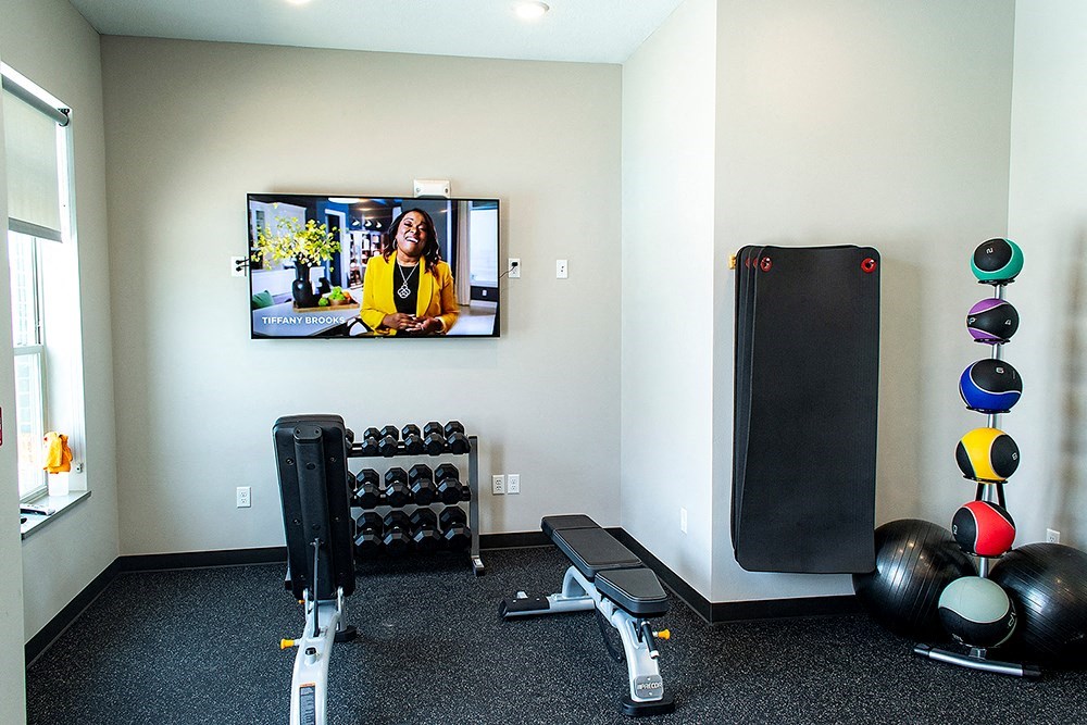 a gym with weights and a tv on the wall