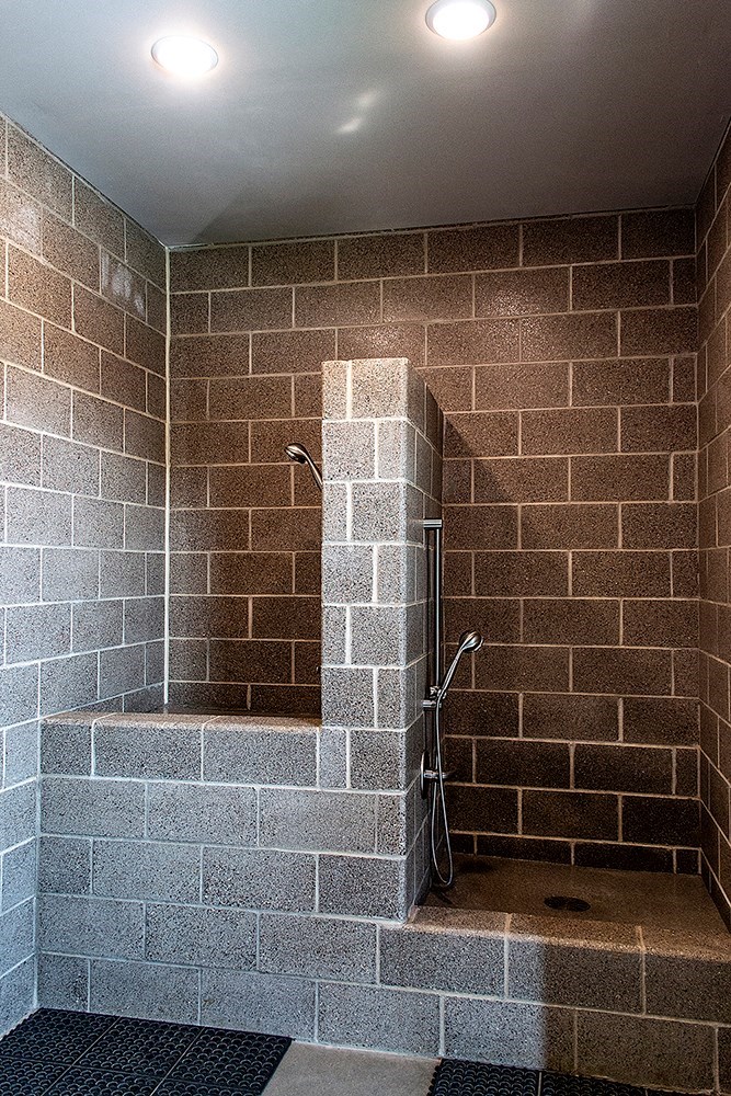 a bathroom with a shower and a brick wall
