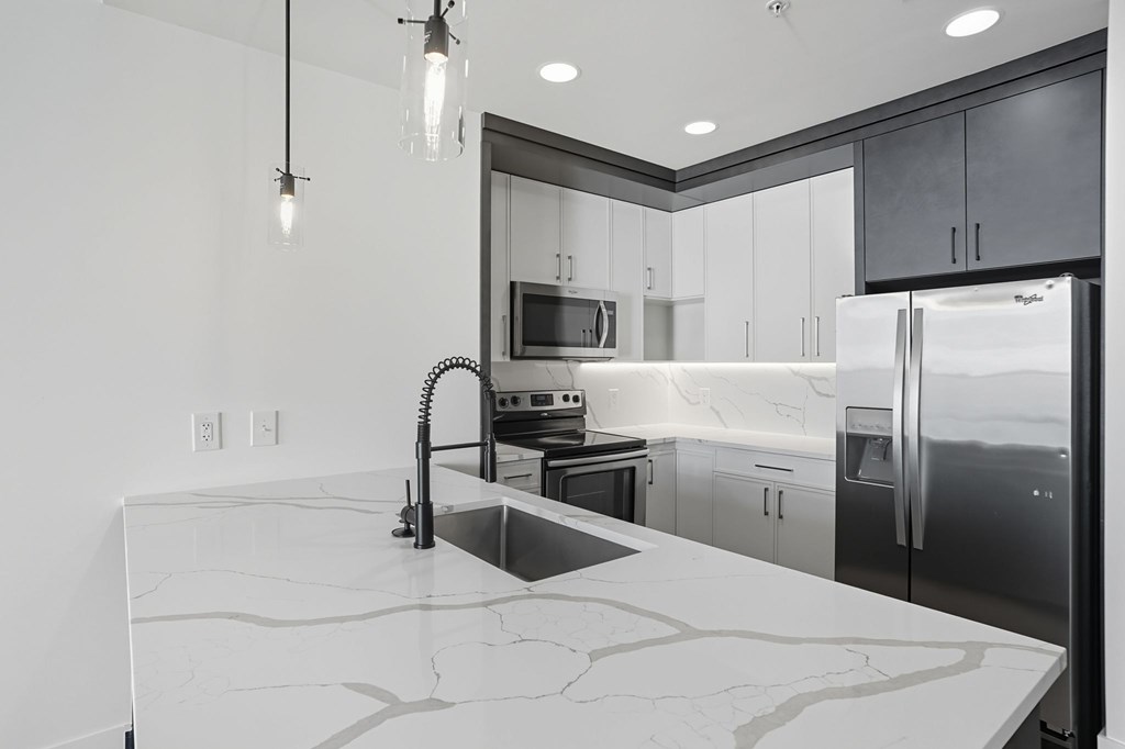 A modern kitchen with a marble countertop and stainless steel appliances.