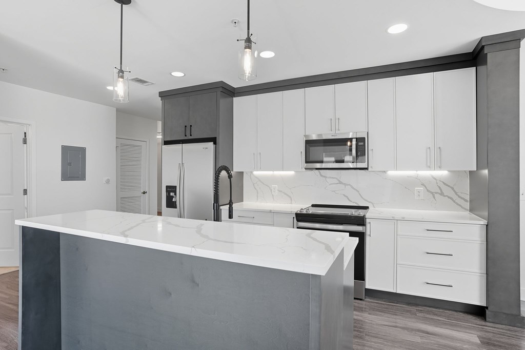 A modern kitchen with a white countertop and dark cabinets.