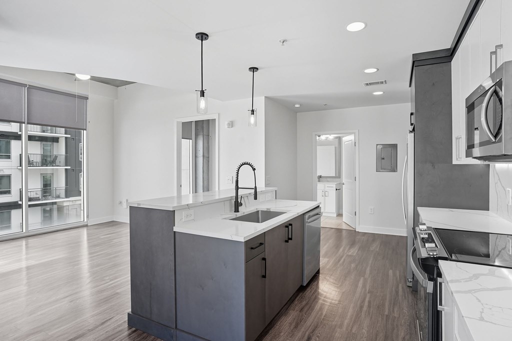 A modern kitchen with a large island and pendant lights.