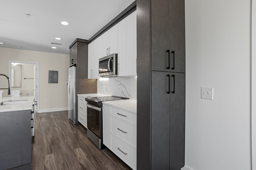 A modern kitchen with dark wood floors and white cabinets.