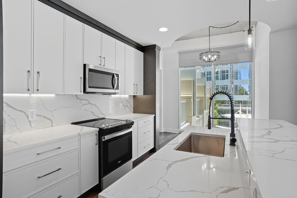 A modern kitchen with white cabinets and marble countertops.