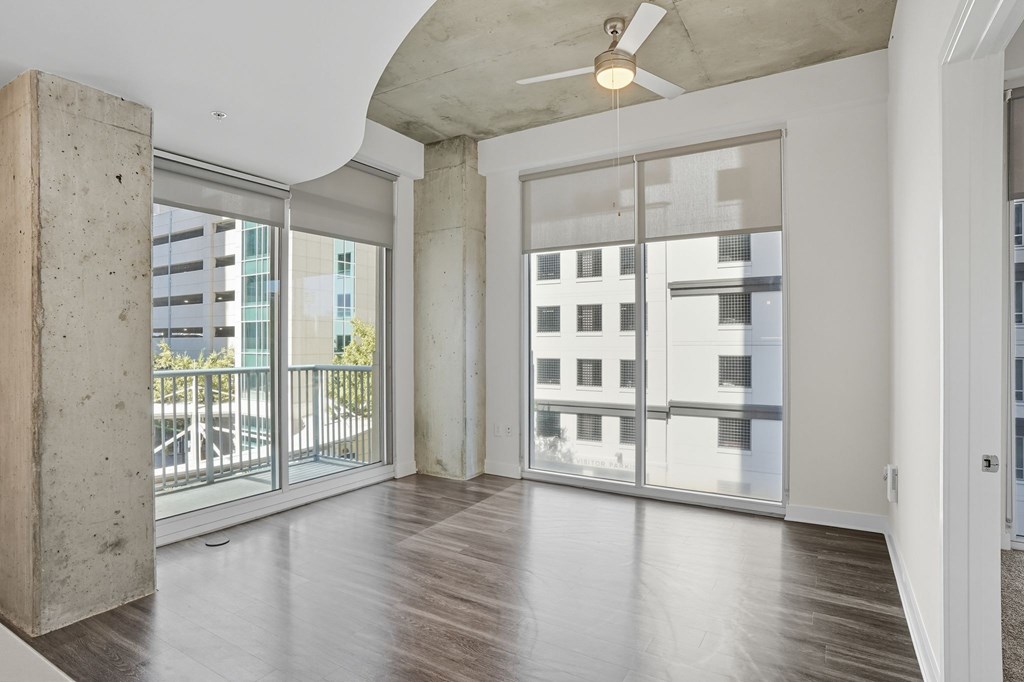 A room with a ceiling fan and sliding glass doors.