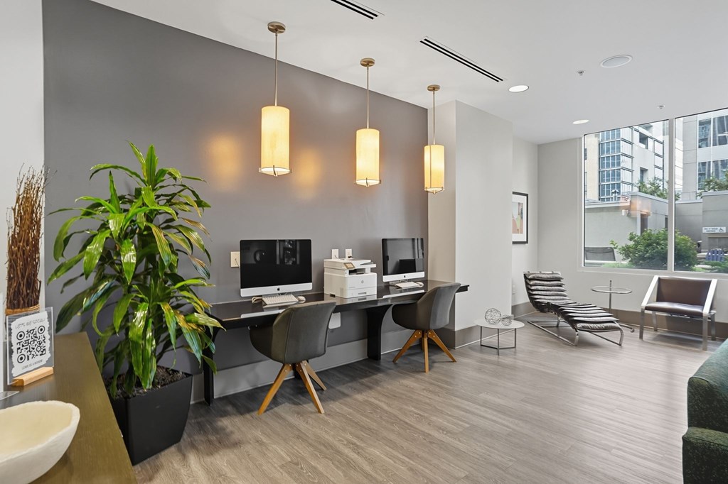 A modern office space with a large desk, chairs, and a plant.