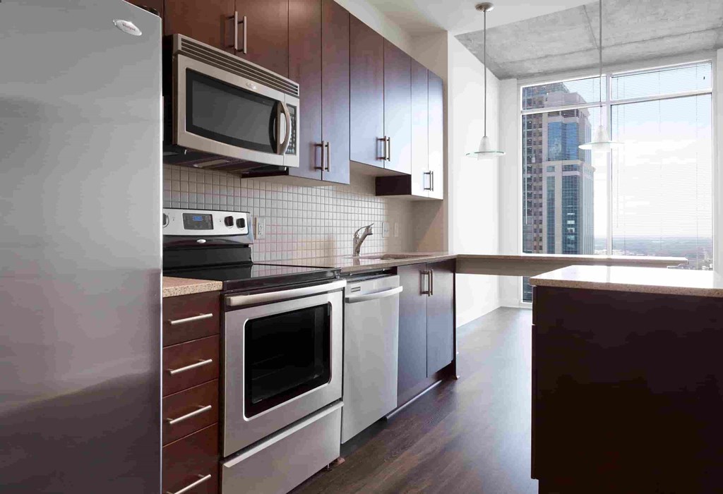 A modern kitchen with dark wood cabinets and stainless steel appliances.