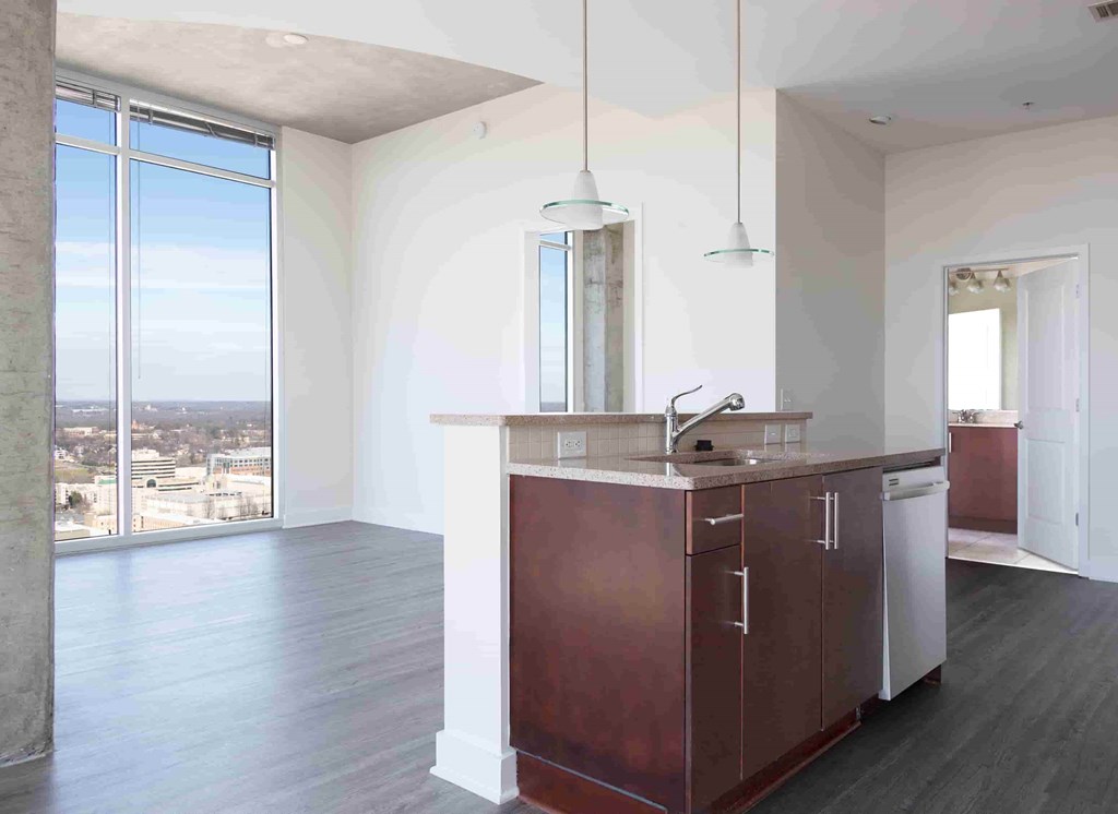 A kitchen with dark brown cabinets and a large window overlooking a cityscape.
