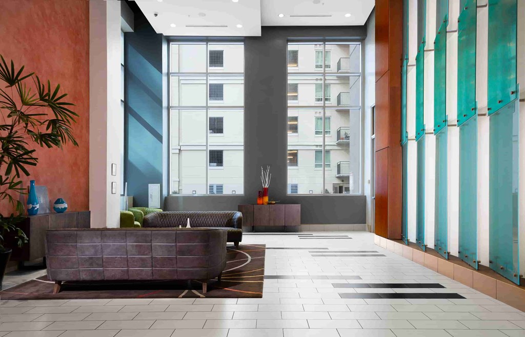 A modern lobby with a large plant on the left and a long bench in the middle.