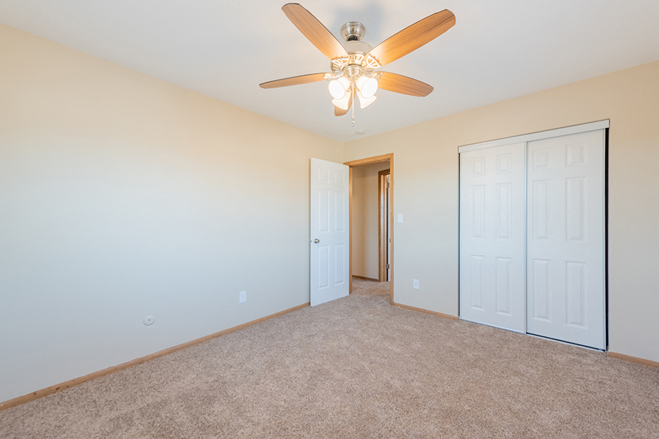 a bedroom with a ceiling fan and a closet