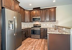A kitchen with wooden cabinets and a marble backsplash.
