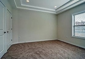 A room with a carpeted floor and a window with blinds.