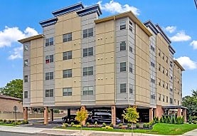 A large tan and brown building with a parking lot in front.