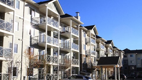 a large apartment building with balconies and cars parked in front