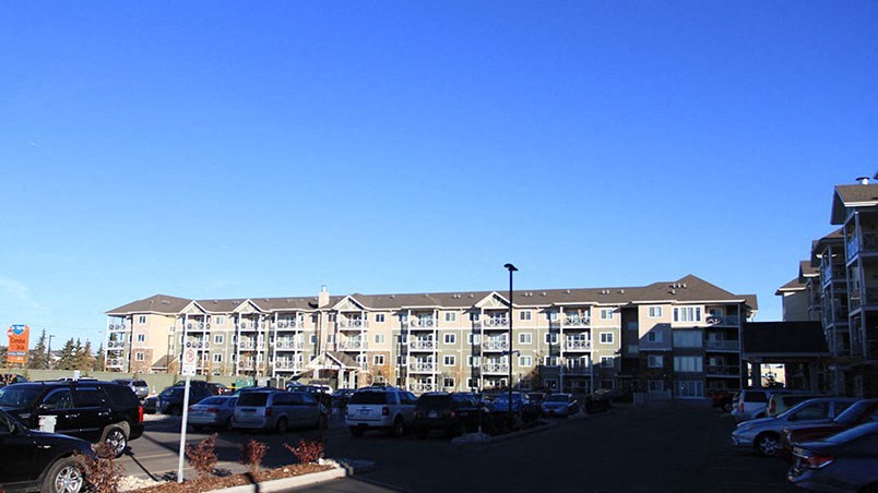 a parking lot full of cars in front of an apartment building