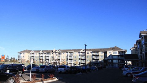 a parking lot full of cars in front of an apartment building