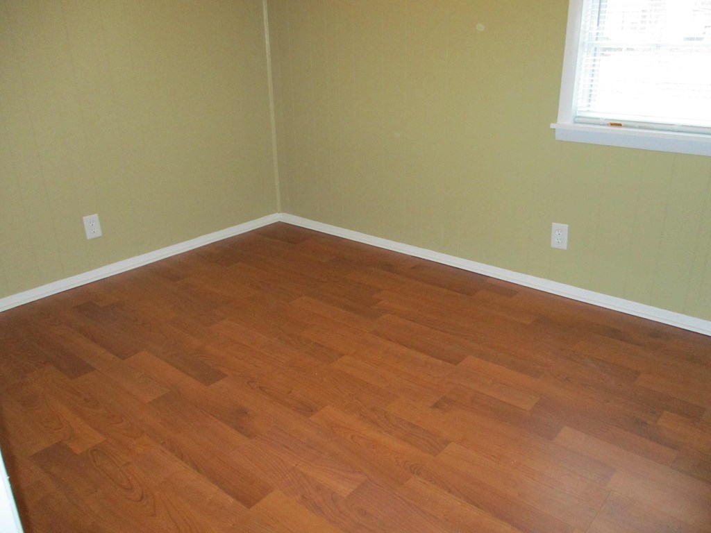 an empty room with wooden floors and a window