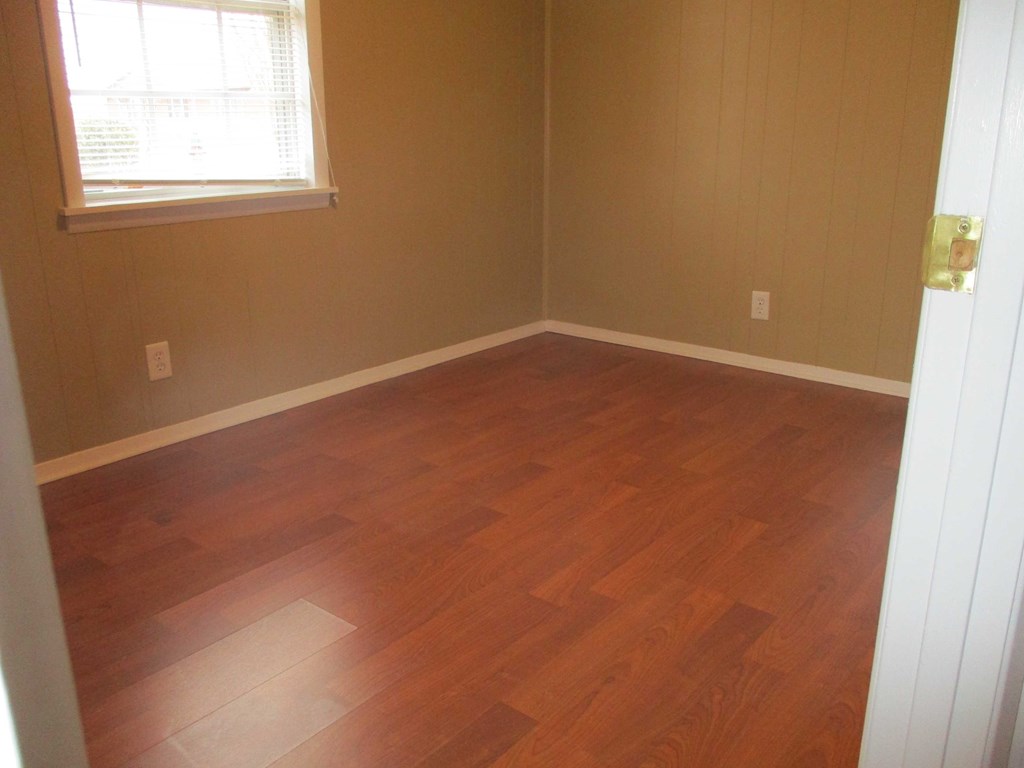 an empty room with wooden floors and a window