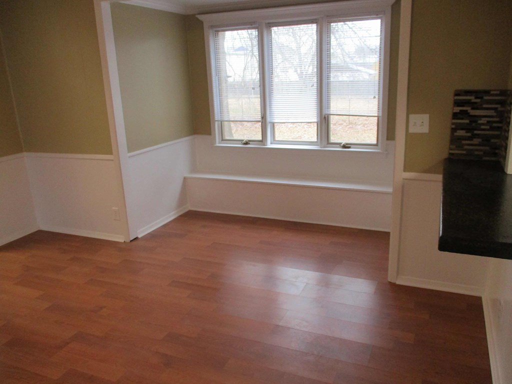 an empty living room with a wooden floor and a window