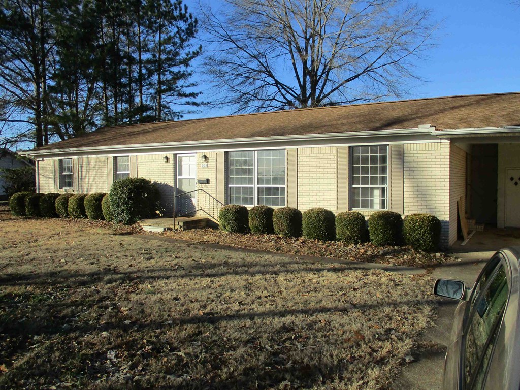 a small yellow house with a yard in front of it