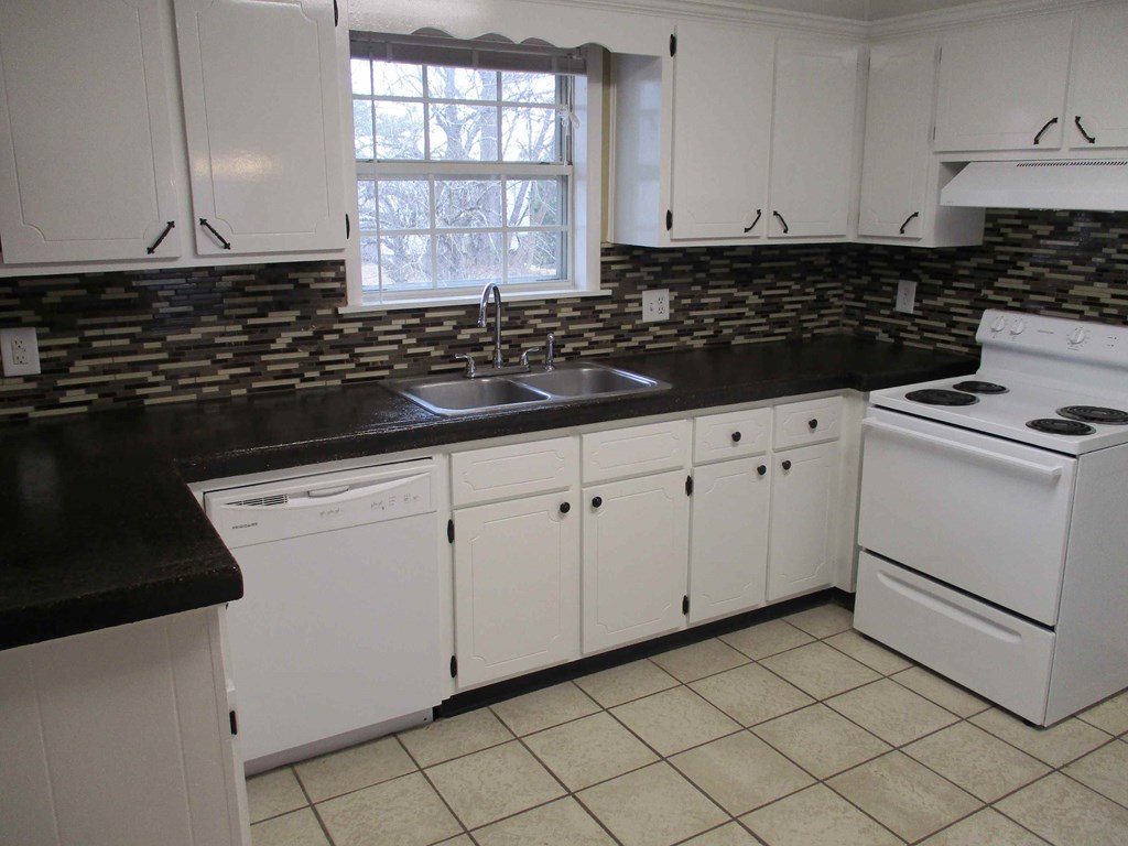 a kitchen with white appliances and black counter tops