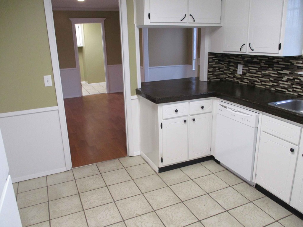 an empty kitchen with white cabinets and black counter tops