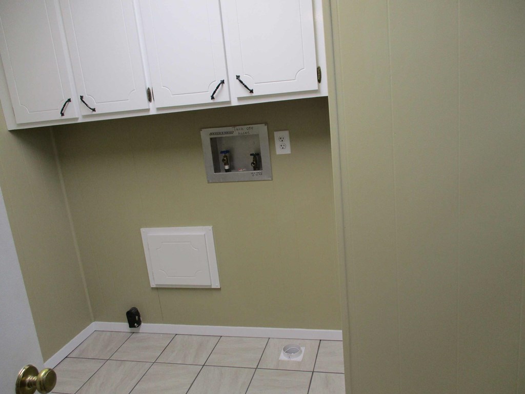 a kitchen with white cabinets and outlets and a tiled floor