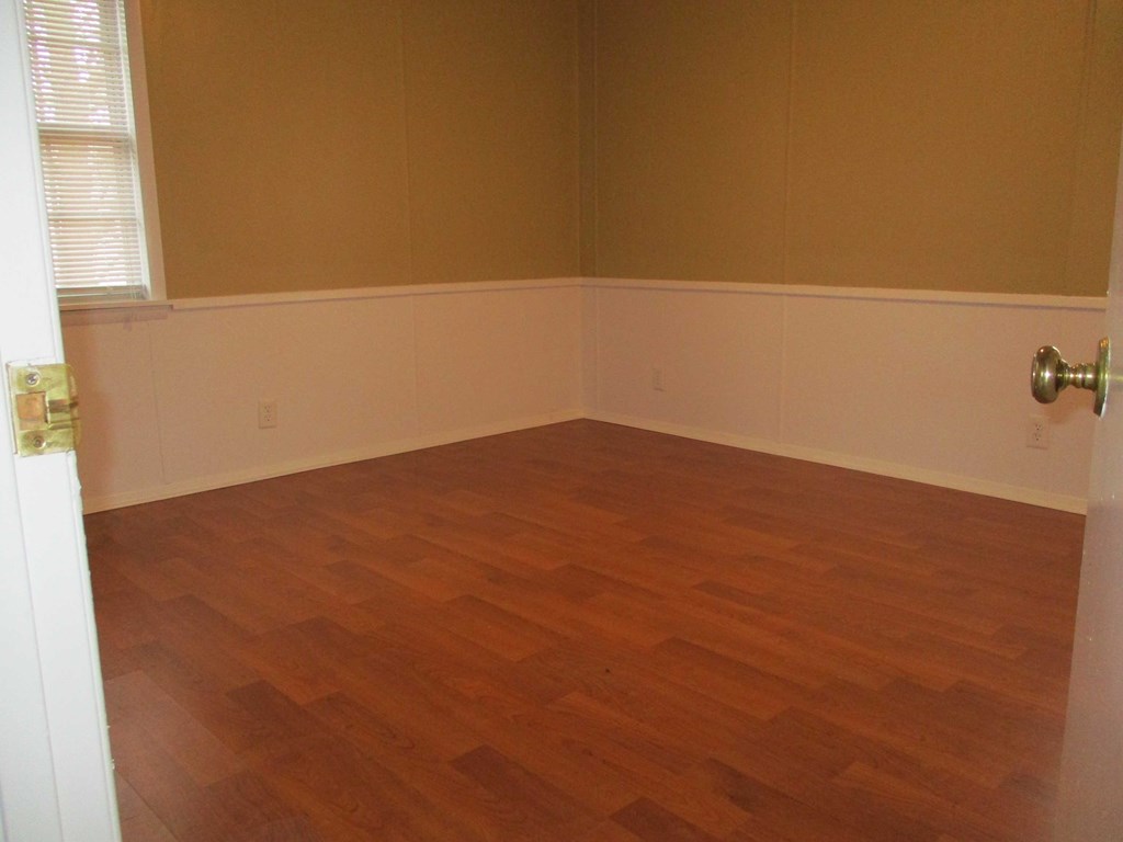 an empty room with wooden floors and a window