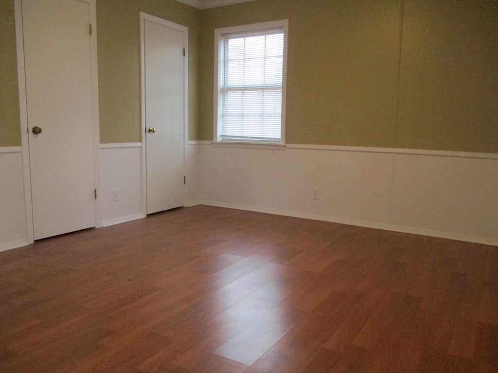 an empty living room with wooden floors and a window