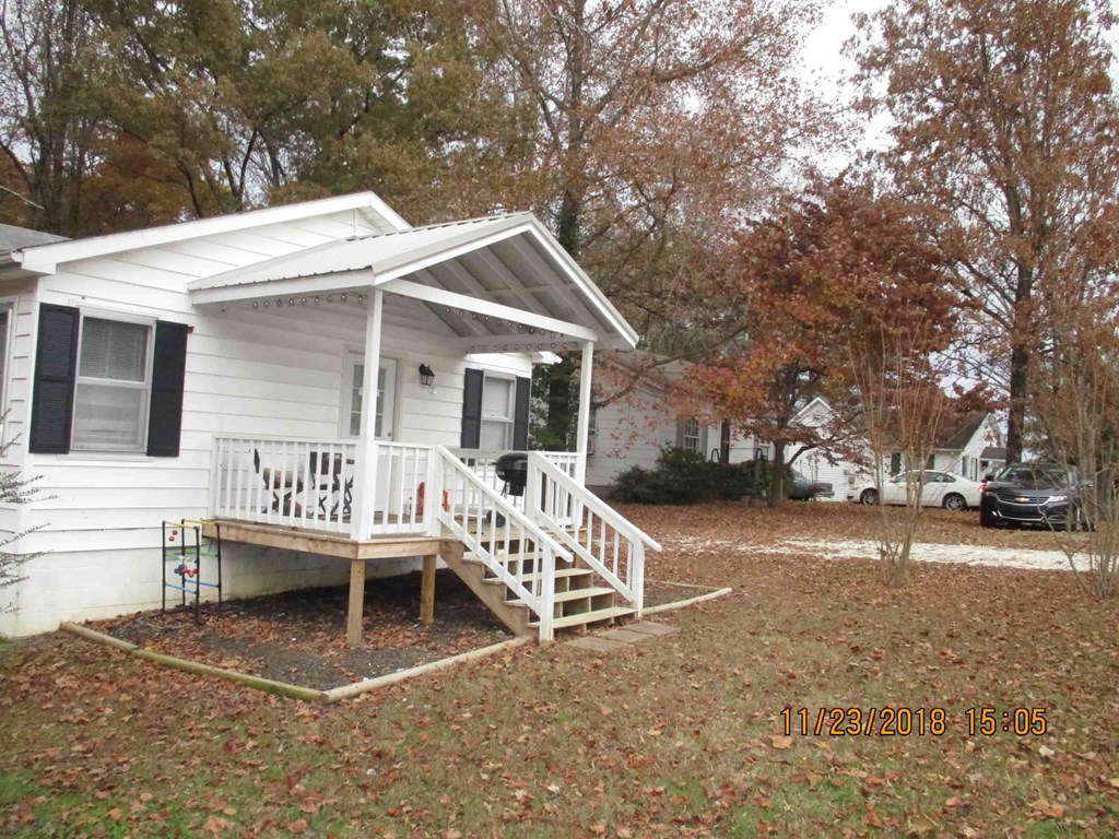 a small white house with a white porch and a front yard