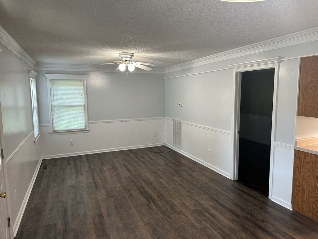 an empty living room with wooden floors and a ceiling fan
