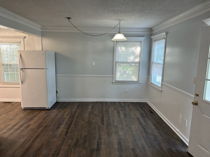 an empty living room with a refrigerator in the corner
