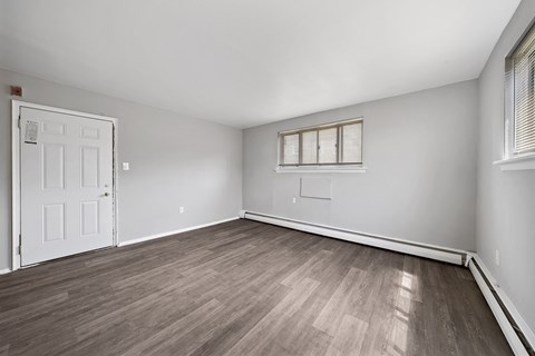 the living room of an apartment with wood flooring and a white door