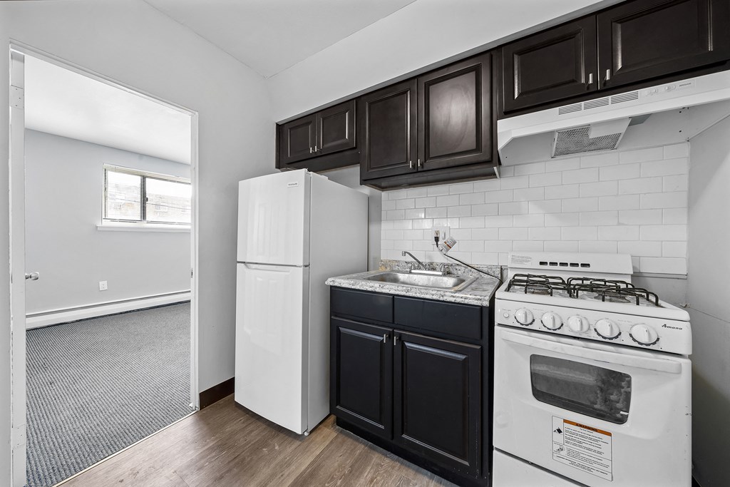 an empty kitchen with white appliances and black cabinets
