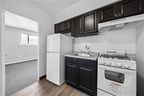 an empty kitchen with white appliances and black cabinets