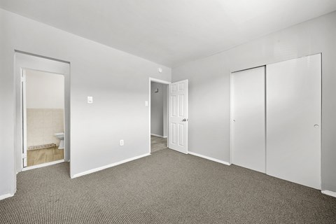 the living room of an apartment with white walls and carpet