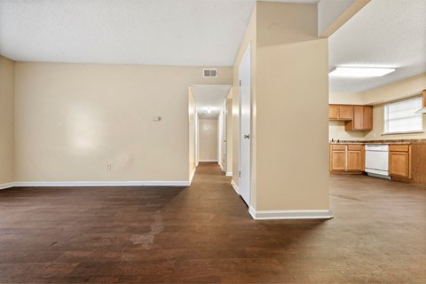 an empty living room and kitchen with wood flooring