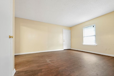 an empty living room with wood floors and a window