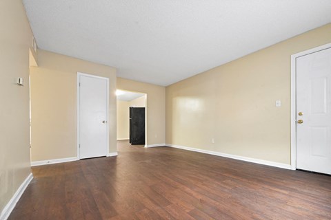 an empty living room with wood flooring and white walls