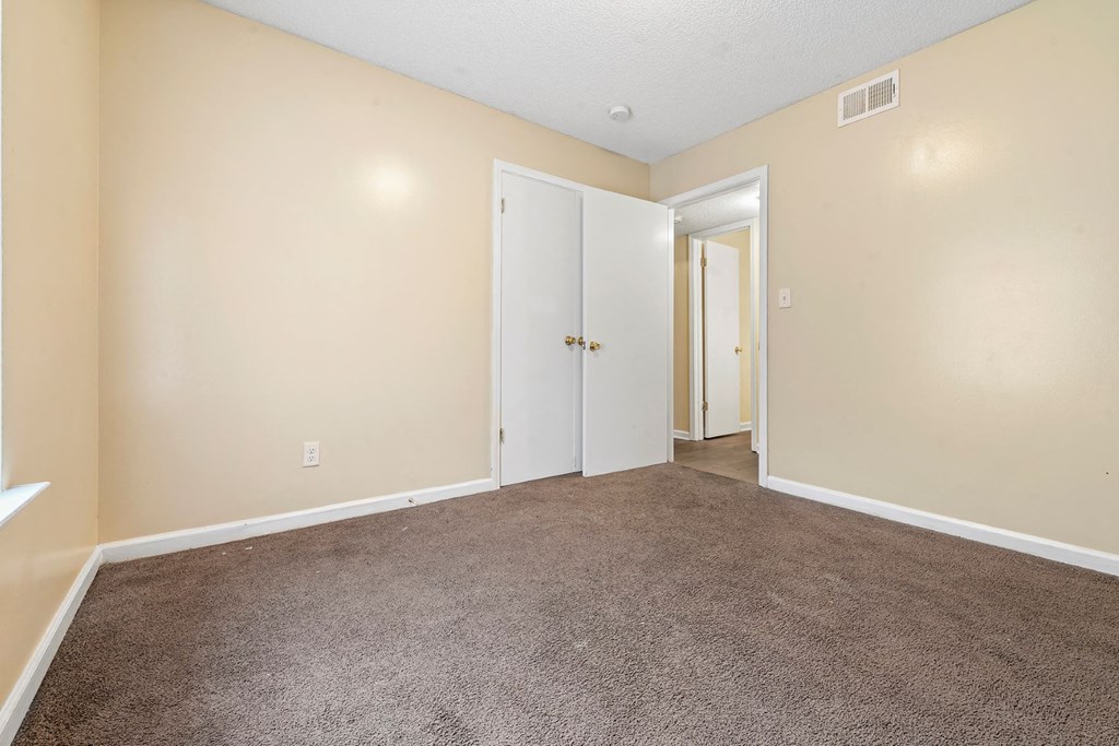 an empty living room with carpet and a door to a hallway