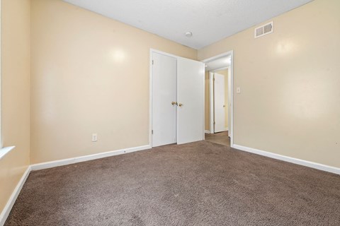 an empty living room with carpet and a door to a hallway