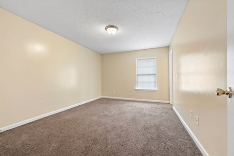 an empty room with carpet and a window