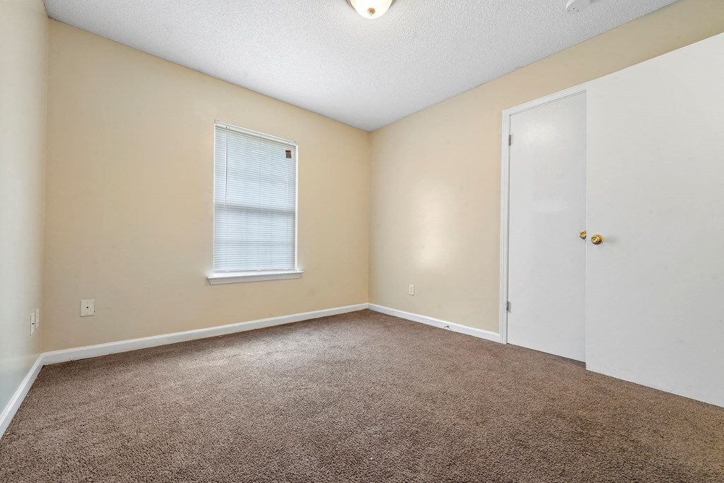 an empty living room with carpet and a white door