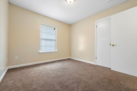 an empty living room with carpet and a white door