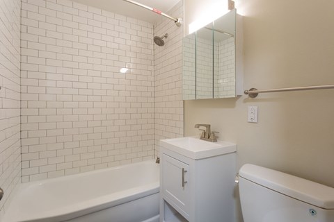 A white bathroom with a white tub, sink, and toilet.