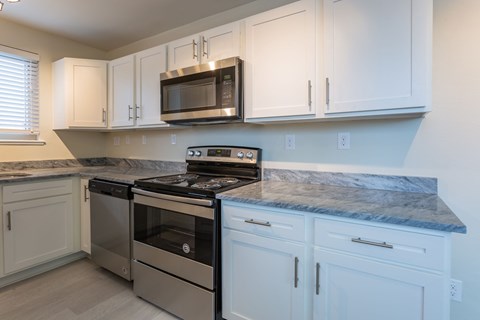 A kitchen with white cabinets and a granite countertop.